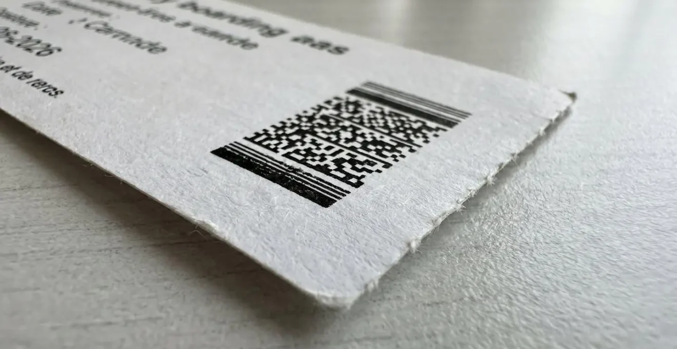 Gros plan extrême sur un billet de ferry avec code-barres visible et détails personnels floutés, posé sur une surface moderne